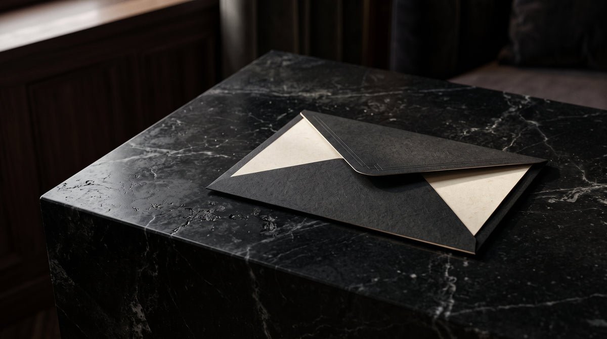 Matte black envelope with an embossed mark on a dark stone table